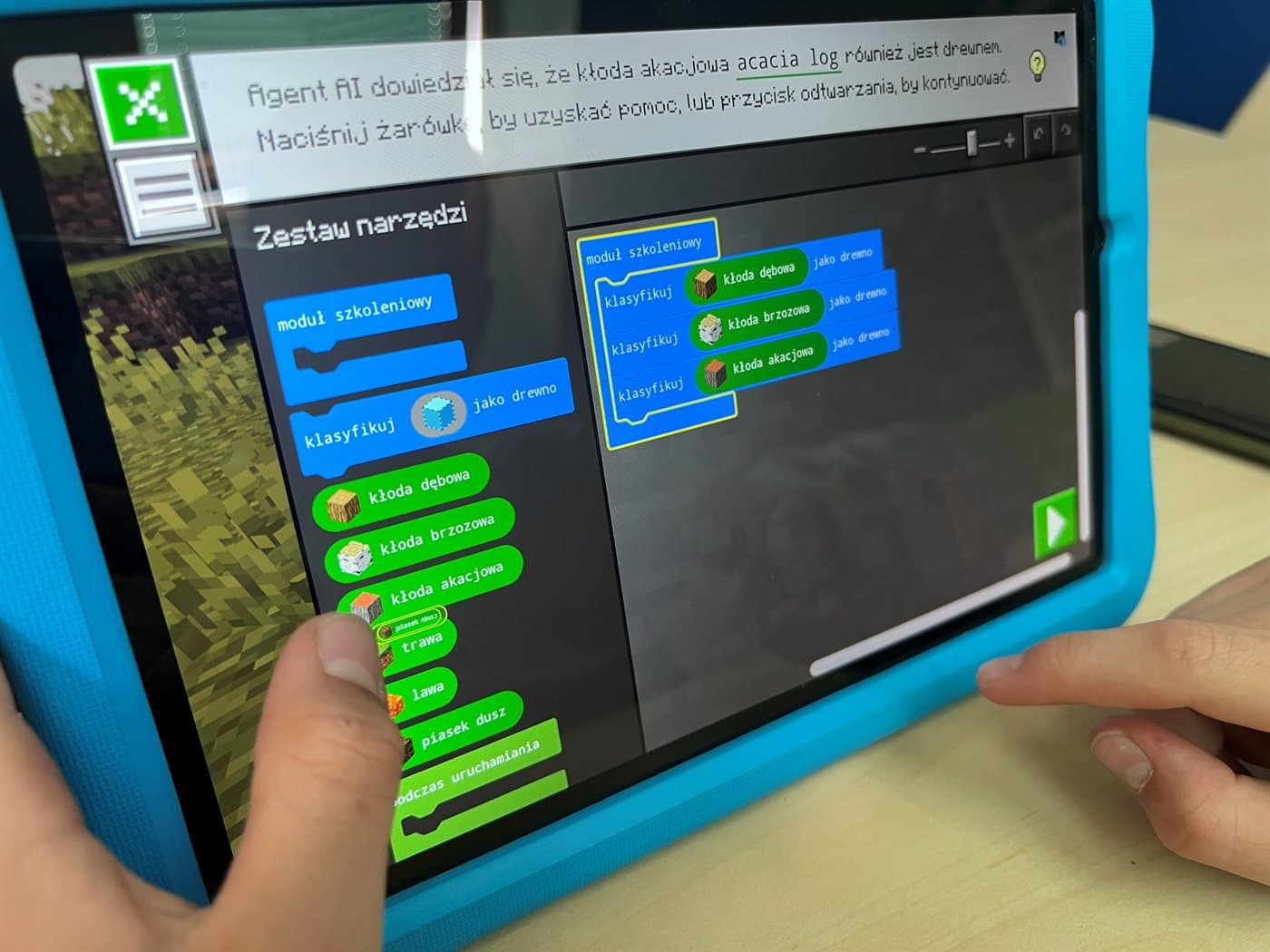 Tablet z edytorem kodu w Minecraft Education - program ułożony z kolorowych bloków